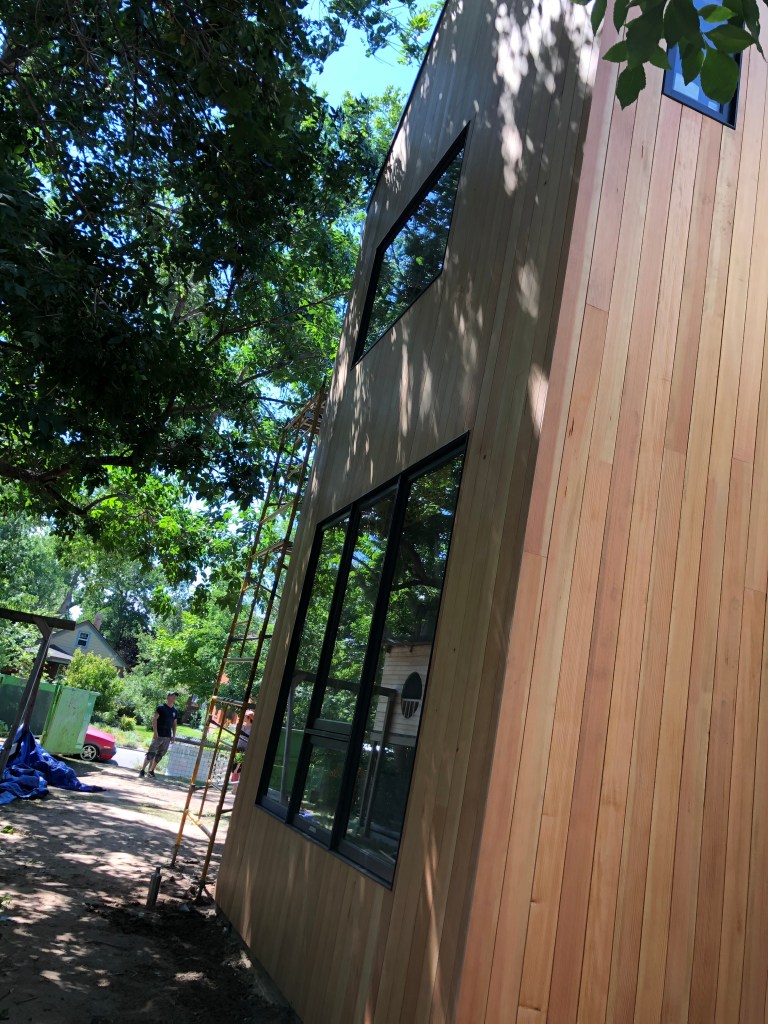 Home exterior update. Wood siding. Vertical siding. Black windows Wood accent