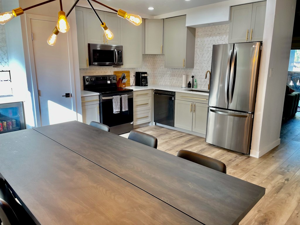 Kitchen remodel. kitchen update. Shaker cabinets, stainless steel appliances. Neutral kitchen. Backsplash. wood dining table. modern sputnik chandelier. Matte black and brass